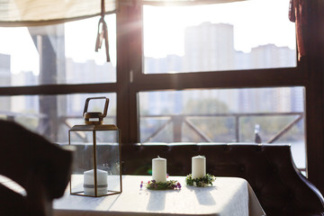 Two candlesticks with burning candles over wooden table