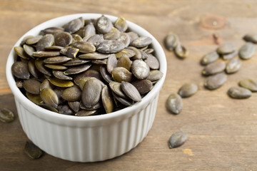 Unshelled pumpkin seeds in white bowl