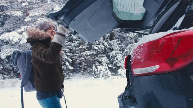 MED Female hiker putting her backpack into a trunk of a modern SUV after a hike in winter forest. 4K UHD, 60 FPS SLO MO, RAW edited footage