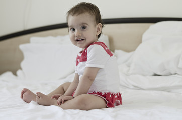 Fototapeta premium Portrait of a beautiful baby girl sitting on bed after a day dream