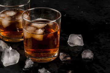 Alcohol whiskey cocktail with cola and ice. On the black table.copy space