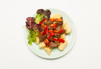 Hot dish of meat with vegetables and salad on a white background. View from above