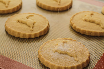 sifting sugar over the shortbread biscuits on the table