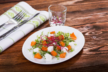 Healthy eating. Warm salad with pumpkin, cheese and mini greens.