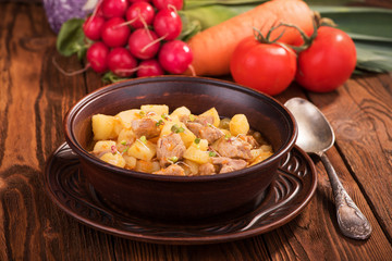 Stew with potatoes and meat in a ceramic plate on a wooden table