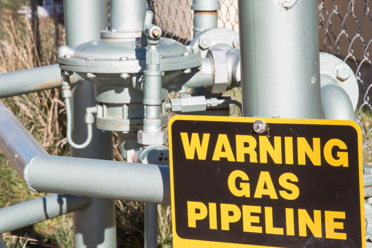 Warning Gas Pipeline sign near exposed pipe