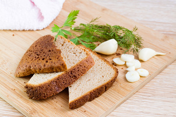 Нарезанный ржаной хлеб, чеснок и зелень