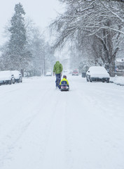 Children walk down the center of an empty street dragging sleds in the freshly fallen winter snow.
