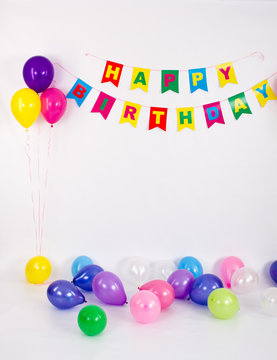 Bright Garland that says happy birthday on a white background with multi-colored balloons