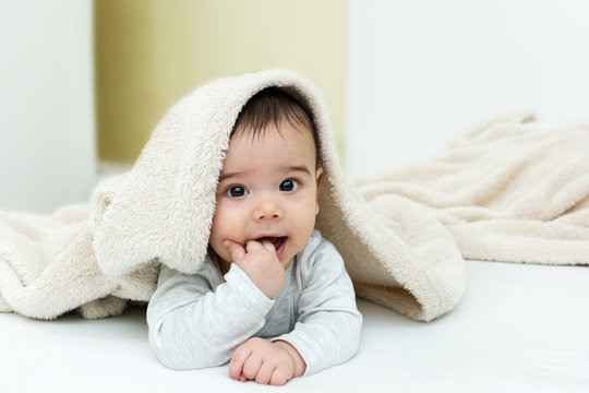 Cute baby boy in bed under a fluffy blanket