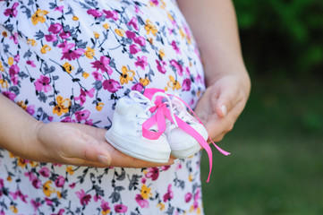 pregnant young mother holds white shoes child