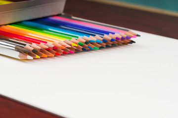 Multicolored pensils in the box on a wooden table.