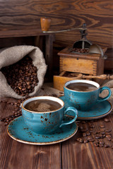 Composition with coffe cup, beans and grinder on burlap texture