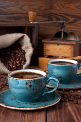 Composition with coffe cup, beans and grinder on on wooden table. 