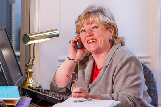 Woman Talking On The Phone At Her Desk