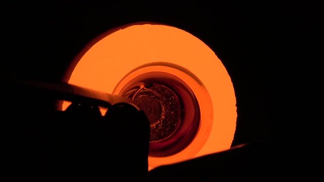 Glassblowing workshop glowing hot oven glassblower gaffer inserting rod with liquid glass vase into furnace showing warm orange yellow color of crystal in hot furnace opening glassmith technique 4k