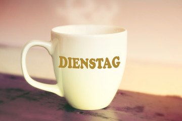 closeup of white cup with the german word Tuesday