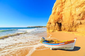 Fishing boat on a Praia da Rocha in Portimao, Algarve region, Portugal - obrazy, fototapety, plakaty