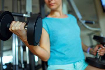Fototapeta premium Woman with dumbbells in the gym doing exercises
