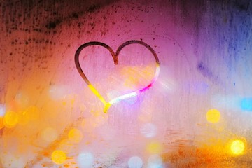 Abstract background - heart painted on a misted window on the background of colorful city lights at...