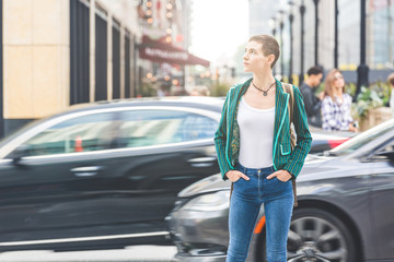 Naklejka na ściany i meble Woman in the city with blurred cars on background