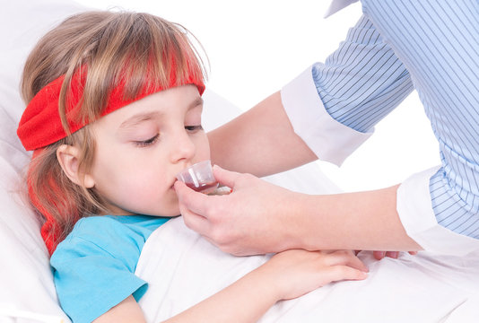 Mother Giving Her Daughter Cough Syrup At Home. Sick Little Girl In Bed Taking Medicine With Plastic Cup. 