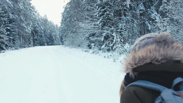 RL PAN Young female hiking with a backpack in beautiful winter forest, turning and smiling into the camera. 4K UHD, 60 FPS SLO MO, RAW edited footage