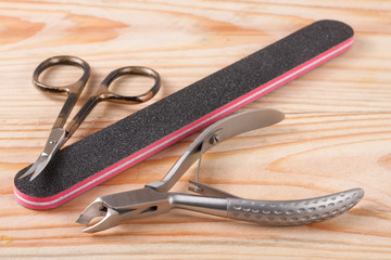 nail scissors file and clippers to remove the cuticle care products on a light wooden background