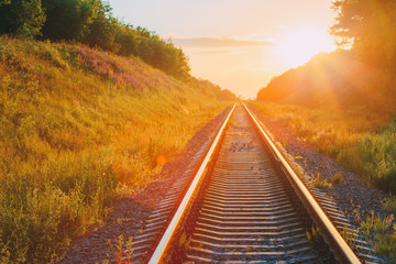 Obraz premium Railway Going Straight Ahead Through Summer Hilly Meadow To Sunset