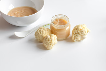 baby mashed with spoon in glass jar on white background