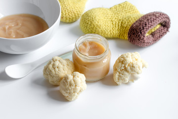 baby mashed with spoon in glass jar on white background