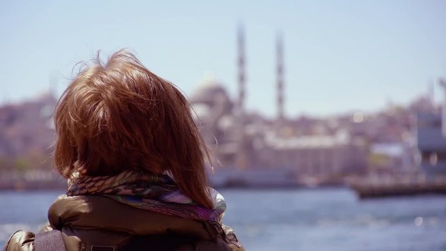 SLOW MOTION: young woman makes video / photo using smartphone app. Pretty red hair girl takes pictures with a phone. Pretty girl at Bosphorus 