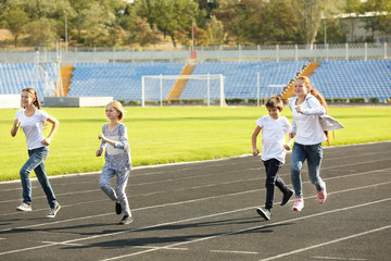 Fototapeta premium Sporty children running on track at stadium