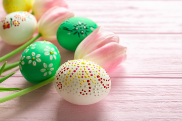 Obraz na płótnie Canvas Colourful Easter eggs with floral ornament and fresh tulips on pink wooden background, closeup