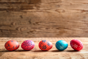 Colourful Easter eggs with floral ornament in a row on wooden background