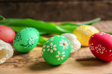 Beautiful Easter eggs and flowers on  wooden background, closeup