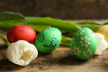 Beautiful Easter eggs and flowers on  wooden background, closeup
