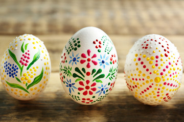 Colourful Easter eggs with floral ornament in a row on wooden background, closeup