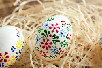 Beautiful Easter eggs with floral ornament in decorative nest, closeup