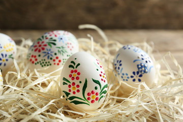 Beautiful Easter eggs with floral ornament in decorative nest, closeup