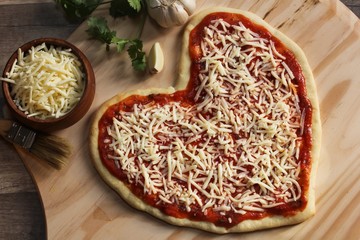 Heart shaped pizza ready to bake overhead view