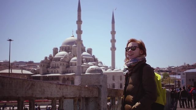 SLOW MOTION: young woman at Galata Bridge in Istanbul. Pretty red hair girl in front of Yeni Valide Sultan Camii in Istanbul.