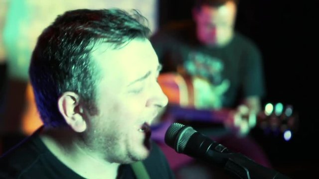 Concert rock band performing on stage with singer performer, guitar, drummer. Music video punk, heavy metal or rock group.