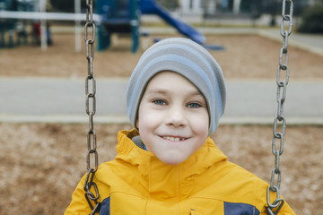 happy boy on a swing. smiling child looking into the camera sitting on a swing