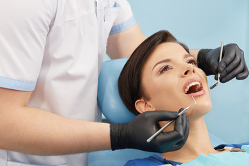 Young female patient visiting dentist office.Beautiful woman with healthy straight white teeth sitting at dental chair with open mouth during a dental procedure.Dental clinic.Stomatology.