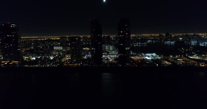 Aerial helicopter tour of a coastal city illuminated at night