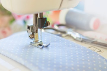 Blurry background of sewing machine working with blue fabric