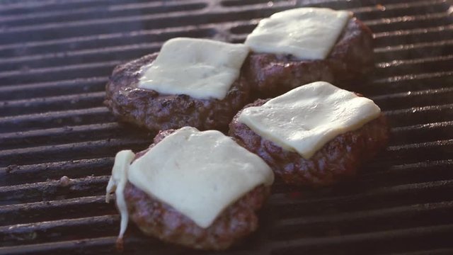 SLOW MOTION: melted cheese on burgers on the grill