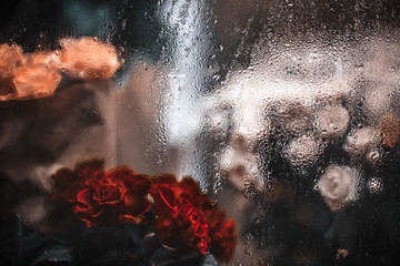 Bouquets of red, white and yellow roses behind window with rain
