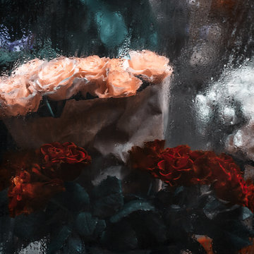 Bouquets of red, white and yellow roses behind window with rain